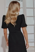 Hover - Black maxi dress with bouffant sleeves, straight top, flared bottom, buckled belt with detachable applique and pointed neckline